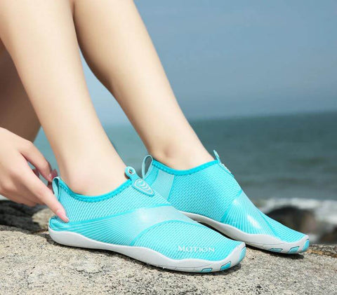 Femme avec chaussures de plage Motion Bleu d'Aquashoes marchant sur le sable