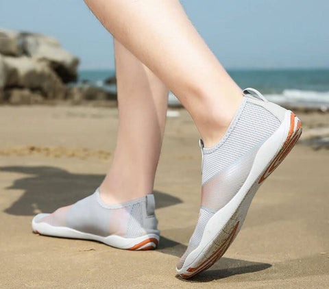 Homme avec chaussures de plage Motion Orange d'Aquashoes marchant sur le sable